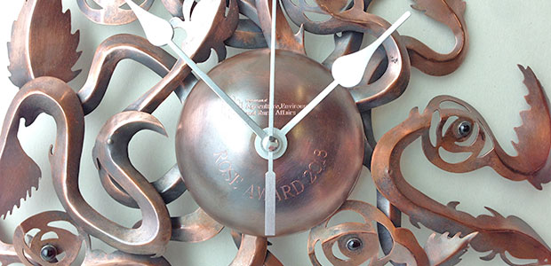 Close-up image of Climbing Roses Clock |  Copper, clock mechanism and garnets | Diameter 27 cm x Height 5 cm | Copper was etched, scored and foldformed. The garnets were bezel set in Sterling silver | Photo credit Leanne McCormack. 